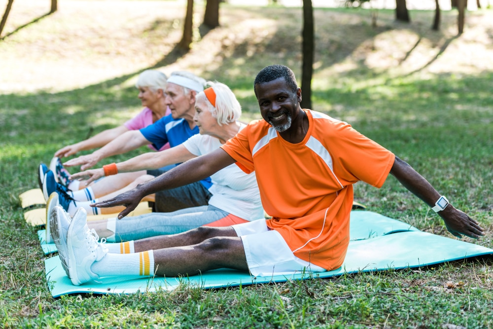  Group of people doing stretching exercises outdoors.