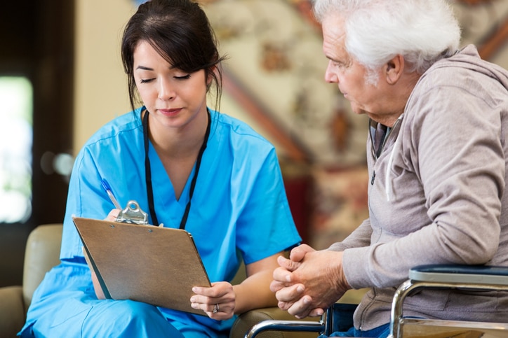 Una profesional de atención médica sentada con un paciente, llenando un formulario médico.