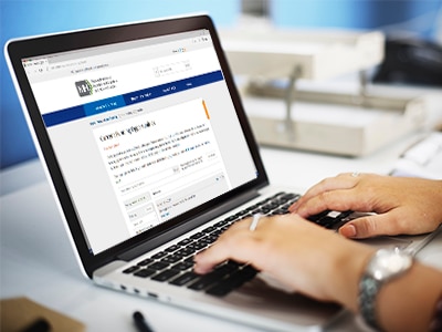 A photograph of hands typing on a laptop keyboard.