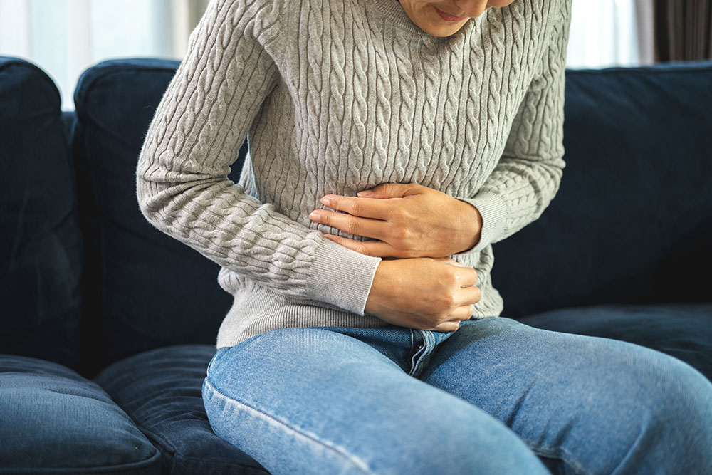 An image showing a woman holding her stomach due to stomach ache