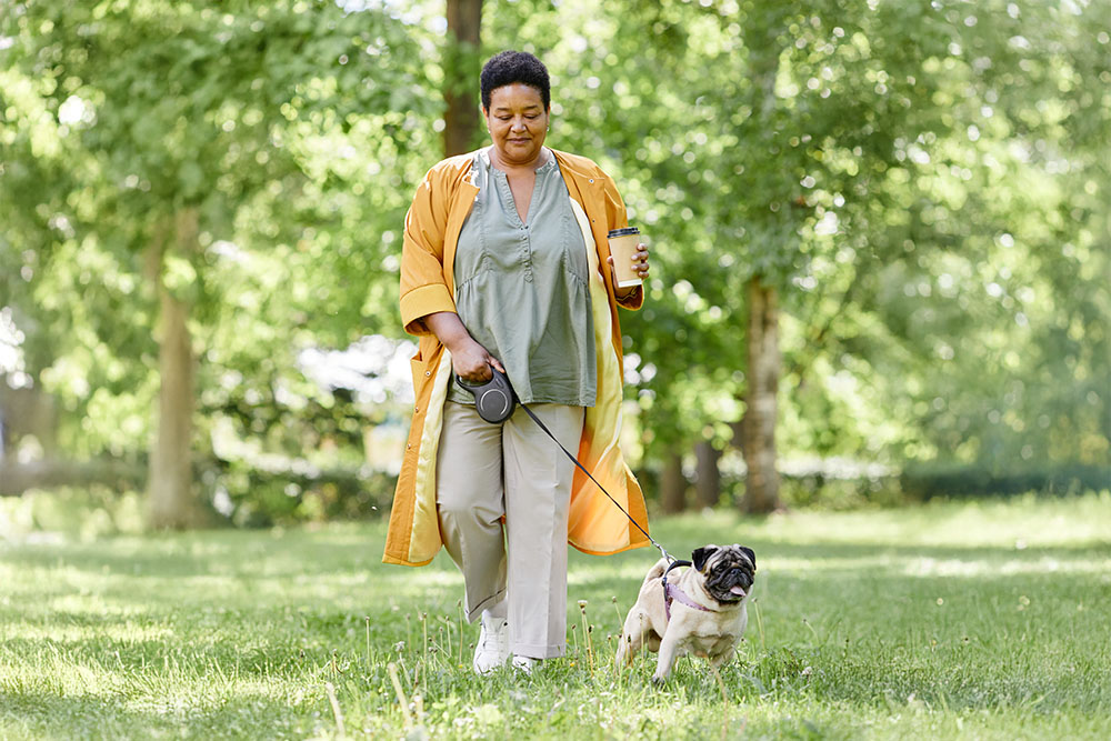 A full-length portrait of a smiling woman with a dog