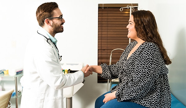 Side view of a doctor shaking hands with a female patient at his office