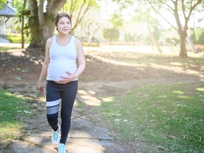 A pregnant woman walking in a park.