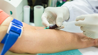 A health care professional draws blood from a person's arm.