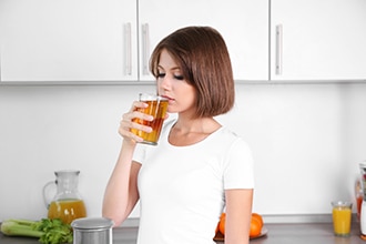 Een vrouw drinkt een glas appelsap.