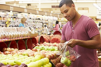 Un hombre comprando frutas en un supermercado.