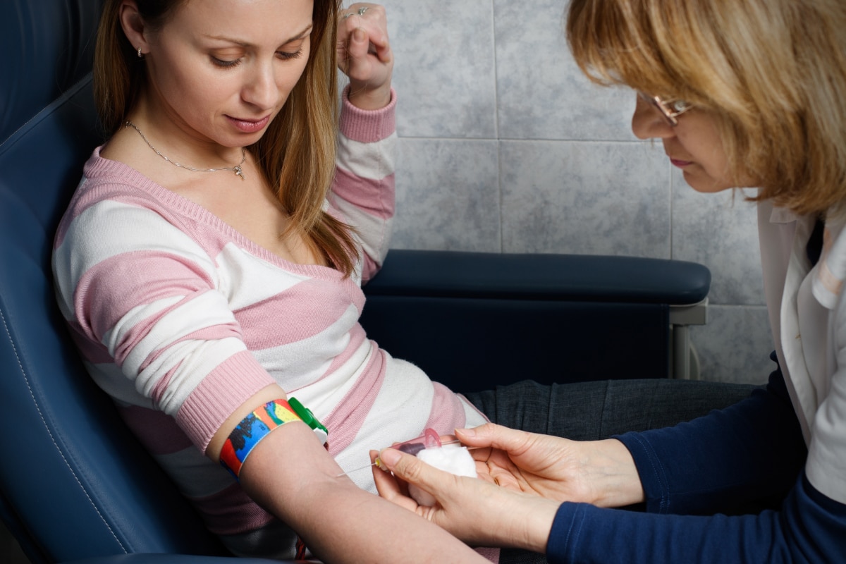 A health care professional drawing blood from a woman’s vein.