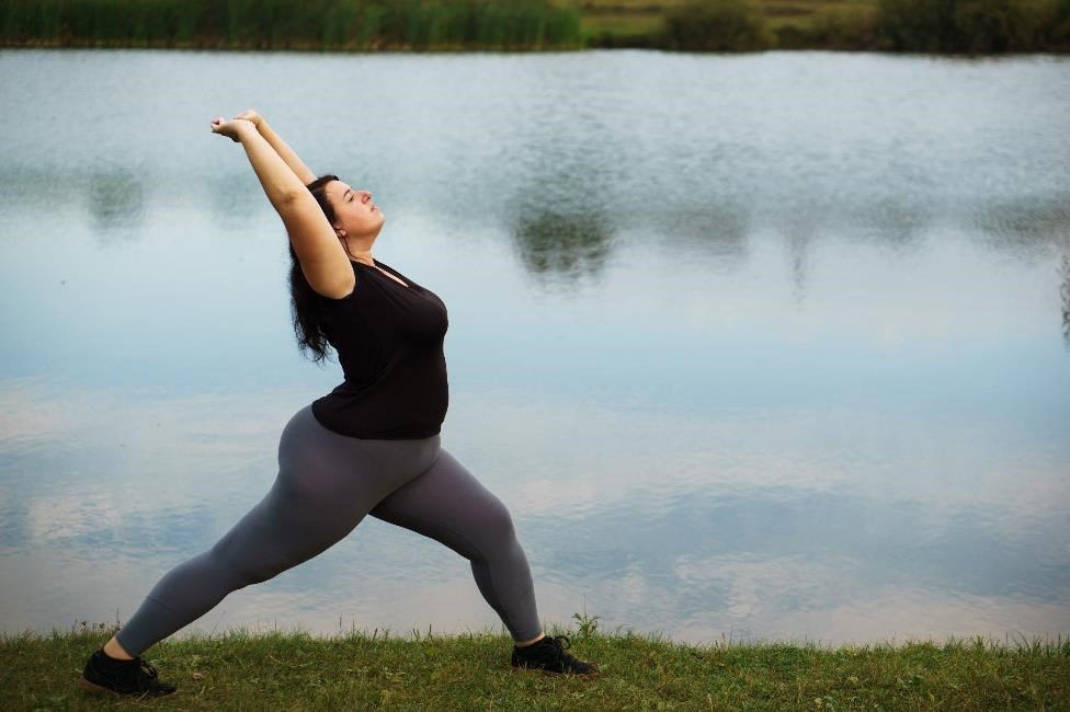 超重女子在公园练习瑜伽。