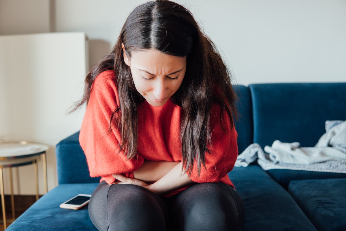 Una mujer con dolor abdominal se agarra el estómago.