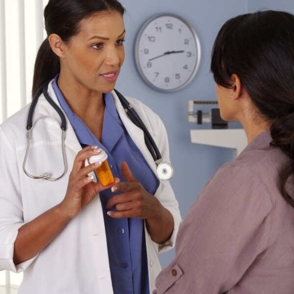 A doctor talks with a patient while holding a prescription bottle.
