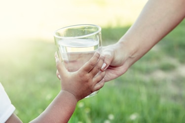 طفل يأخذ كوب ماء من شخص بالغ.