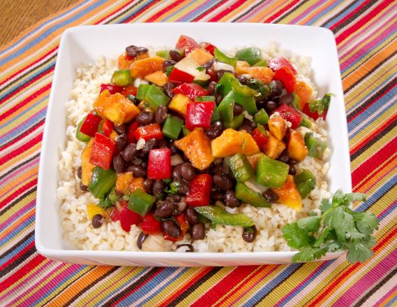 Plato de frijoles negros cocidos con pimientos y arroz integral.