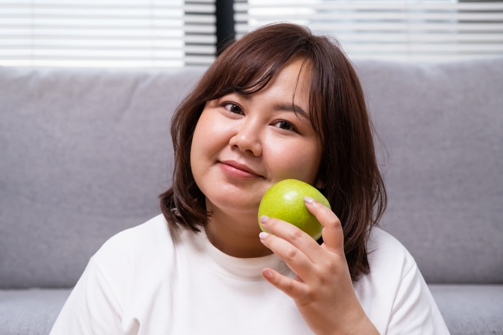 Una adolescente que sostiene una manzana verde.