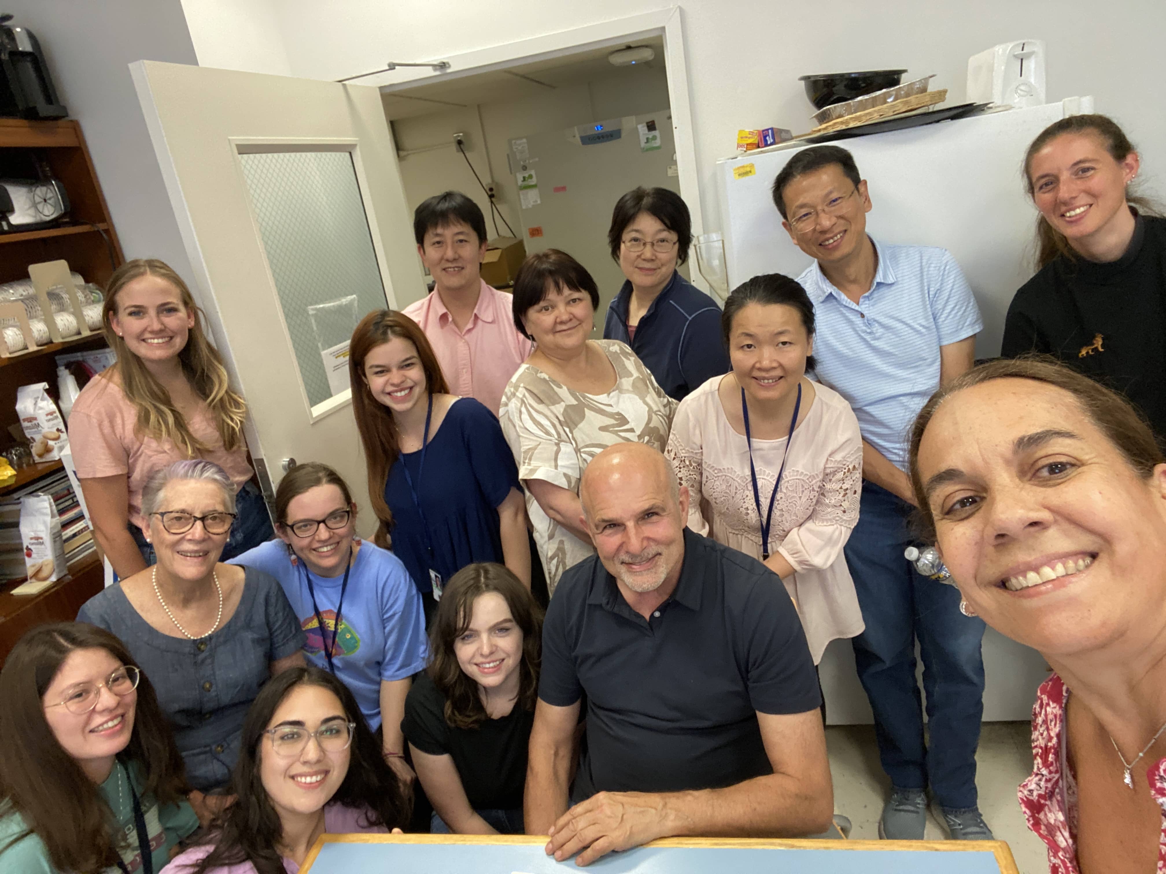 Lab members sitting and standing in a lab and smiling.