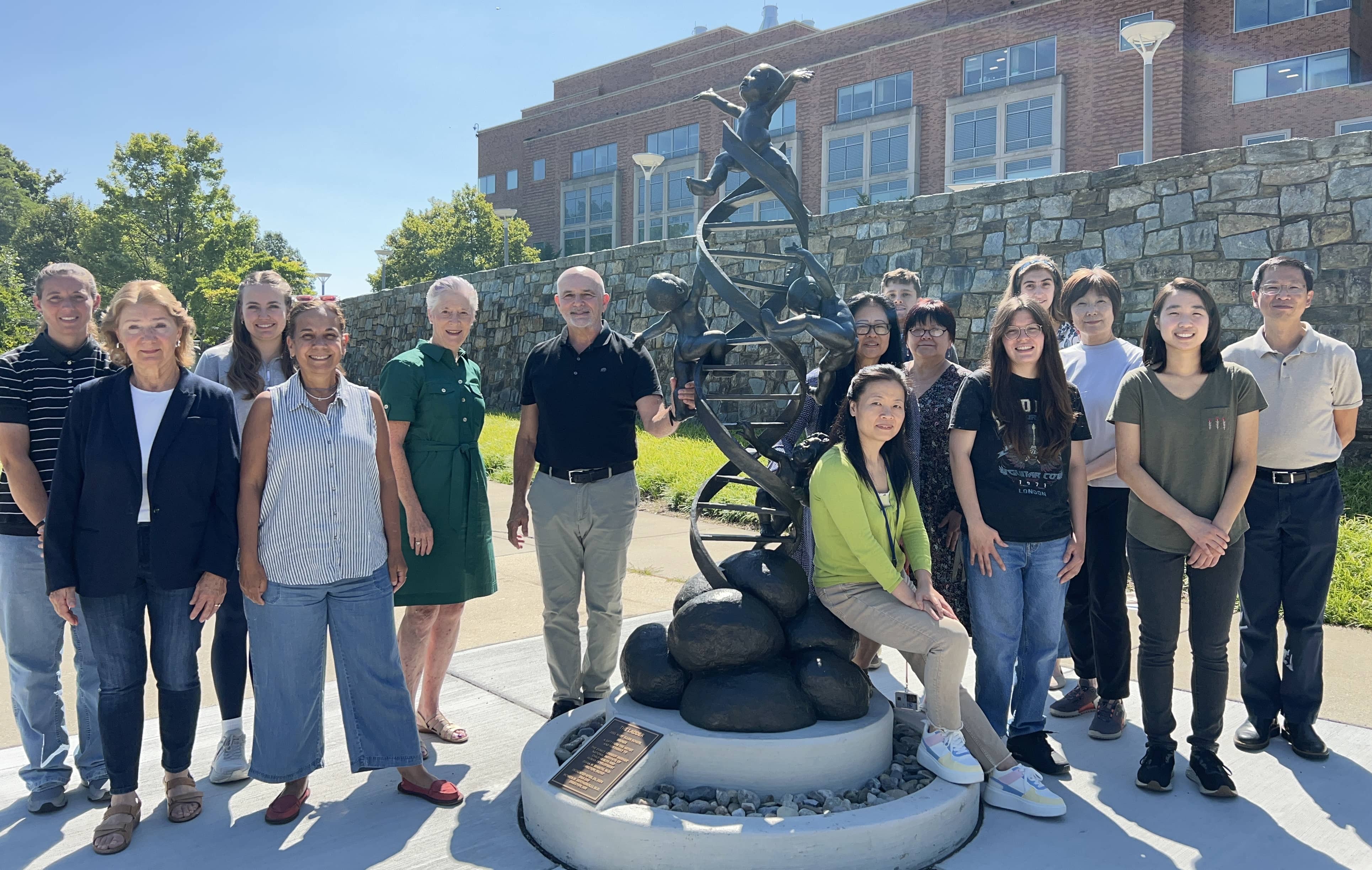 Lab members standing outside around a statue and smiling.