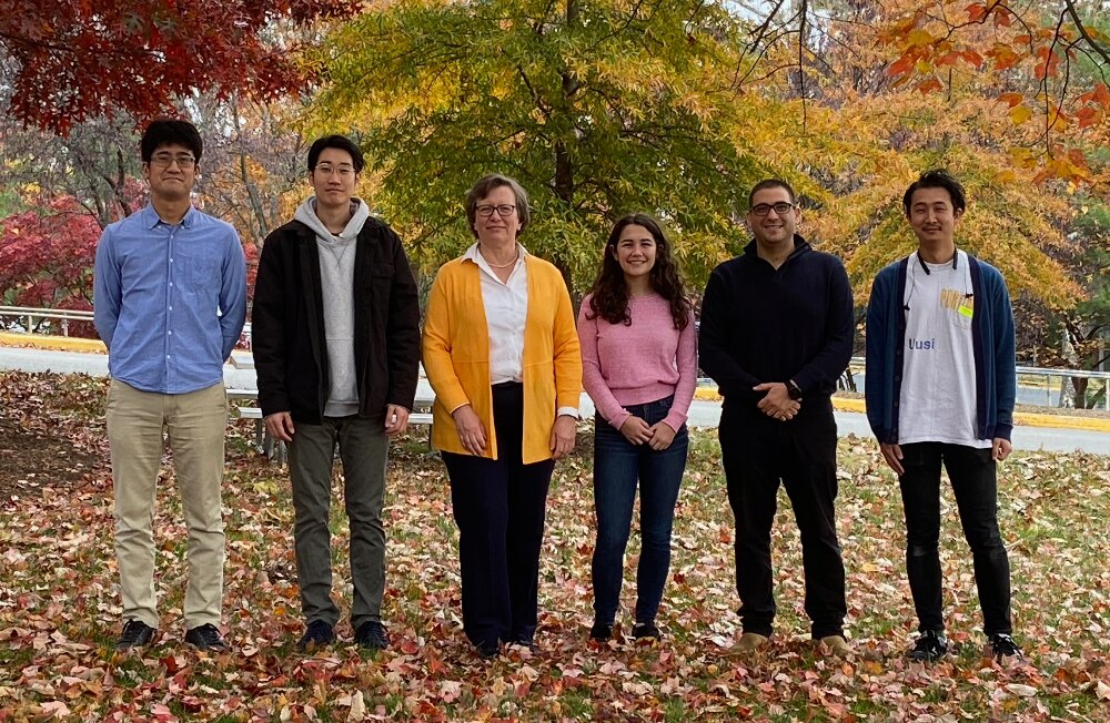 Lab members standing outdoors in front of trees with leaves of many colors